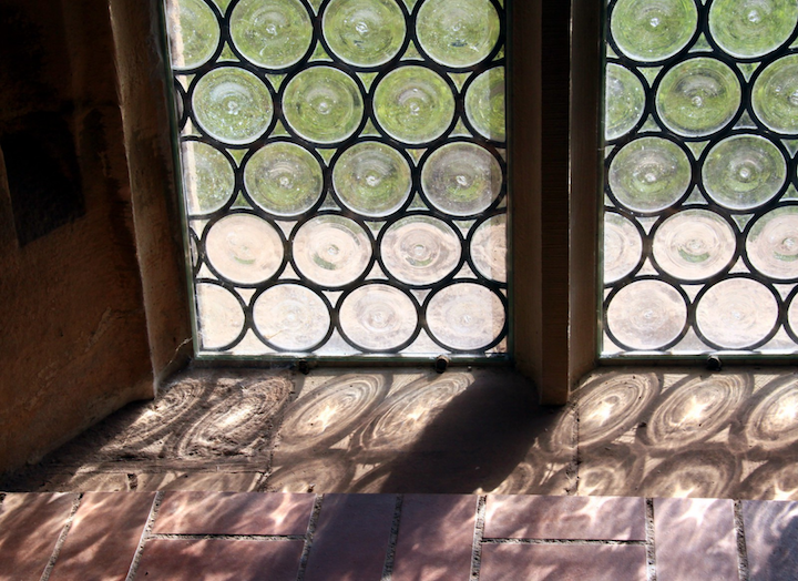 An antique window with small, curcular pieces of glass set together within a window frame.