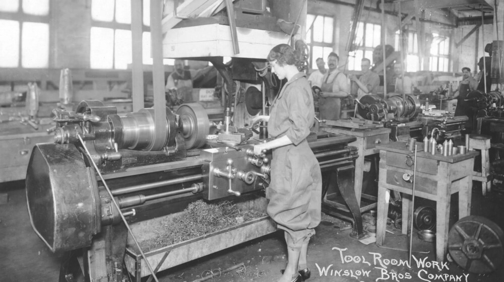 A black and white picture of a woman working in a machine shop during World War One.