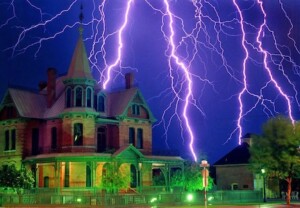 A picture of Rosson House at night with several bolts of lightning in the background.