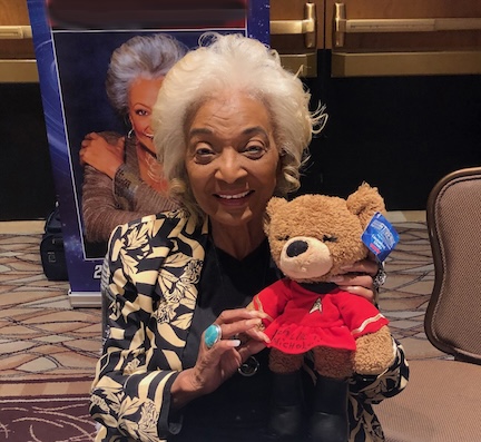 A picture of actor Nichelle Nichols holding a teddy bear in Star Trek uniform.