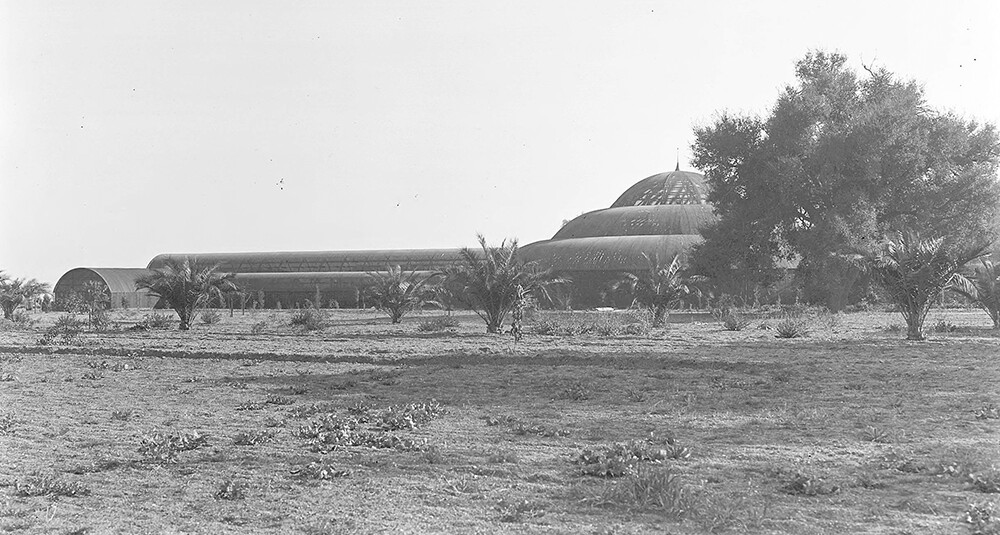 An old, black and white photo of a very large lath house with a dome in the middle.