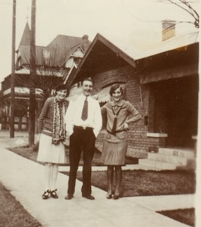 An old, sepia photo from 1928, of three people standing with Rosson House in the background. The upstairs balcony of the house is screened in for use as a sleeping porch.