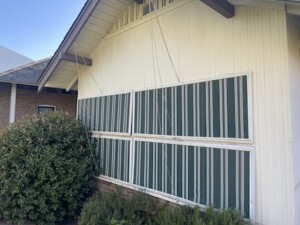 A current day exterior photograph of one of the sleeping porches at the Duplex. It has four horizontal panels that can be raised to allow for better ventilation.