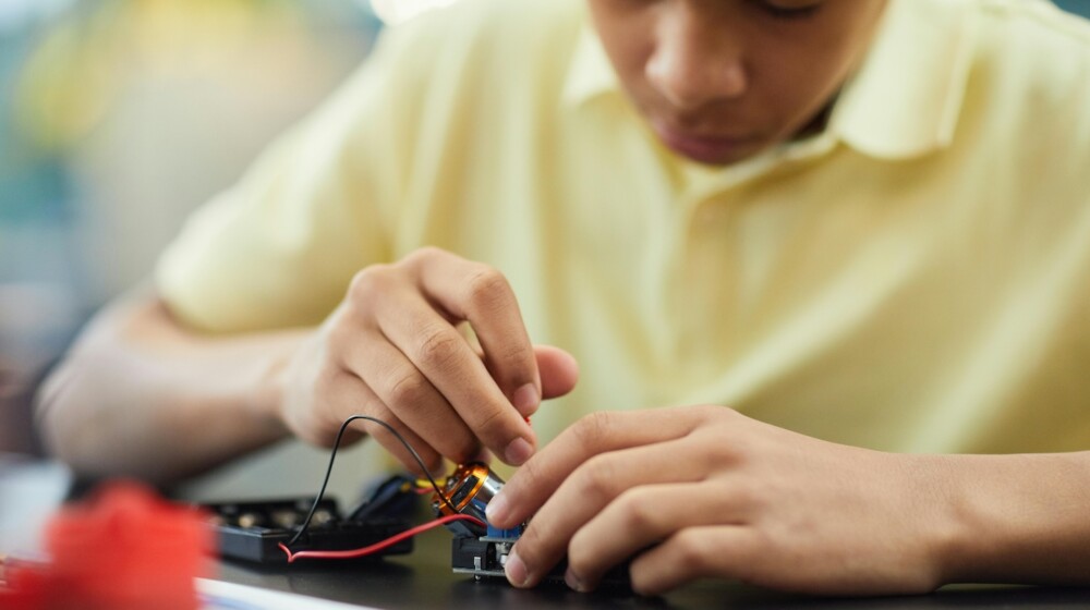 A photograph showing a teenager working on a robotics project.