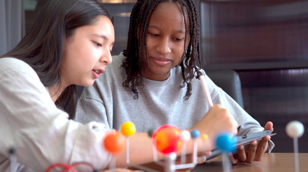 A picture of two students learning about the solar system.